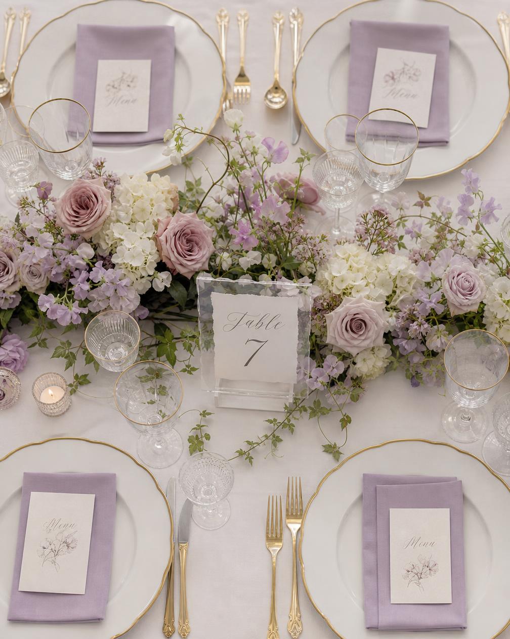 Lilac roses, sweet peas and crystal glassware styled on a soft lavender table
